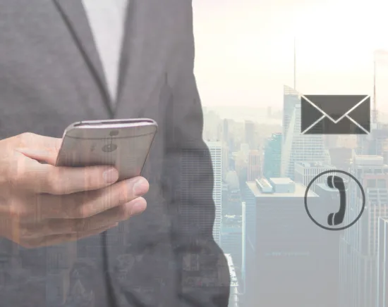 Contact header image showing a person in a suit holding a smartphone over a city skyline background, with phone and email icons representing business contact and communication.